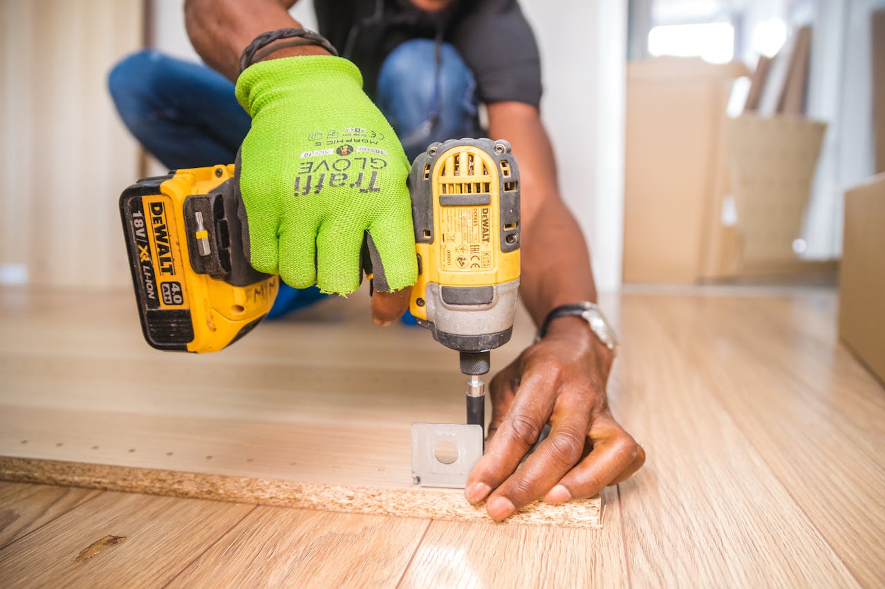 hero-img-02 Man using a power drill for home improvement on a wooden floor with precision.