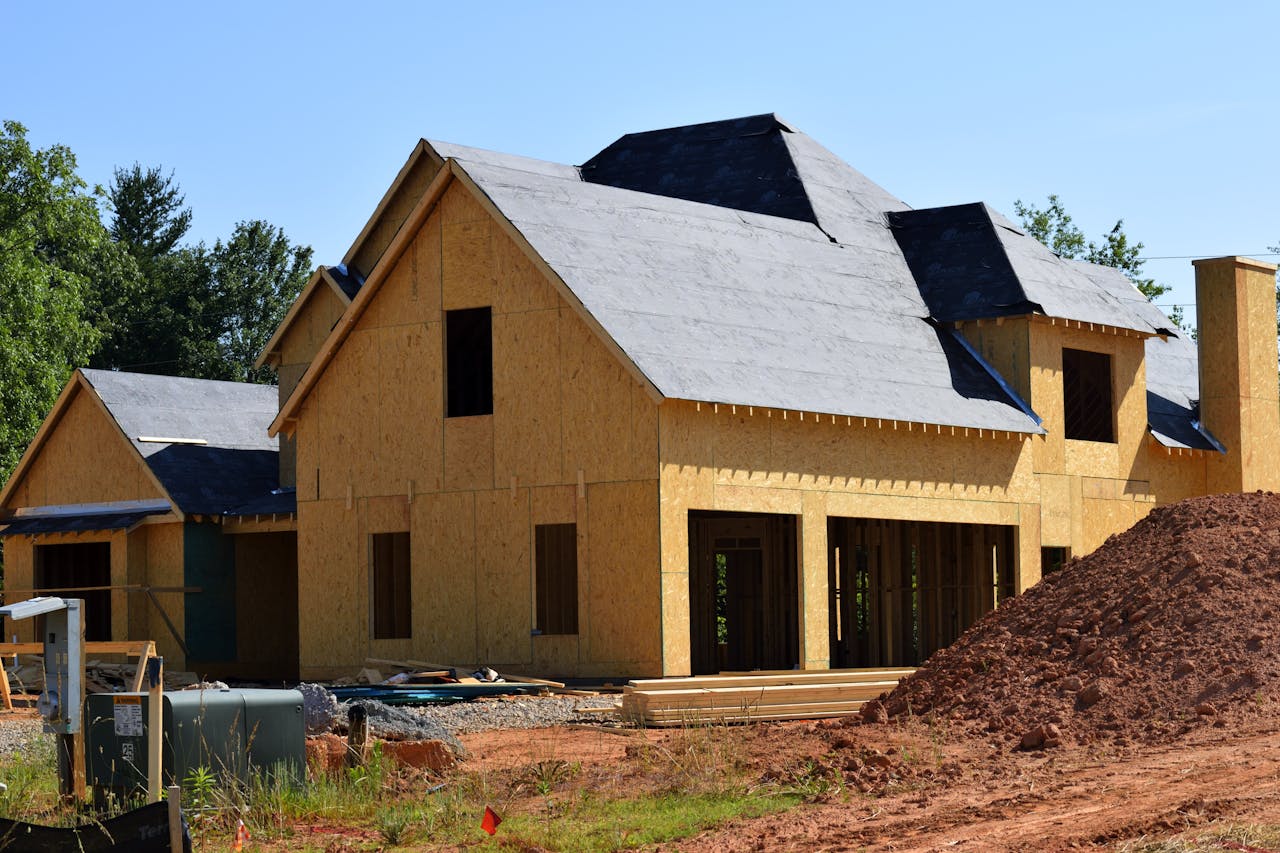 our-services-2 A partially built wooden house under construction, showcasing its progress and design in daylight.
