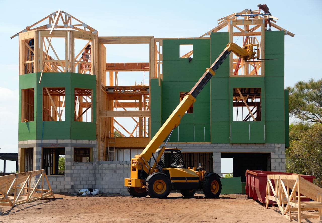 our-services-3 A multi-story wooden house under construction using a crane on a sunny day.