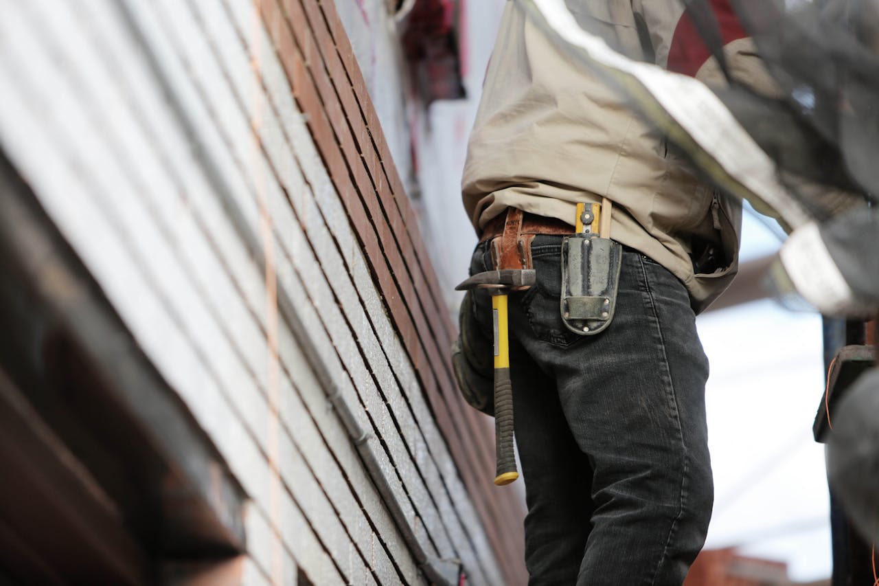 our-services-1 Close-up of a construction worker with hammer and tools, focused on the job.